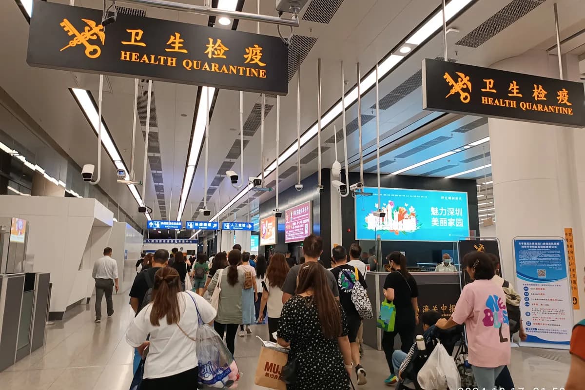 Travelers moving through Futian Port border signage in Shenzhen